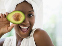 Black woman holding sliced avocado