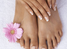 Cropped view of hands on perfectly pedicured feet on a white towel