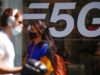 People, wearing protective face masks, walk past a 5G data network sign at a mobile phone store in Paris, France, April 22, 2021. REUTERS/Gonzalo Fuentes