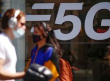 People, wearing protective face masks, walk past a 5G data network sign at a mobile phone store in Paris, France, April 22, 2021. REUTERS/Gonzalo Fuentes